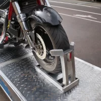 A motorcycle secured in an open car hauling trailer, showcasing personalized transport services by ADL Logistics.
