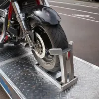 A motorcycle secured in an open car hauling trailer, showcasing personalized transport services by ADL Logistics.